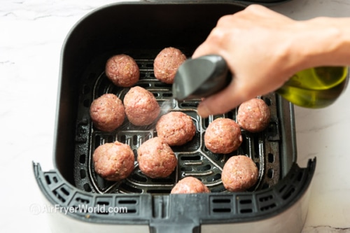 Spraying uncooked meatballs in air fryer