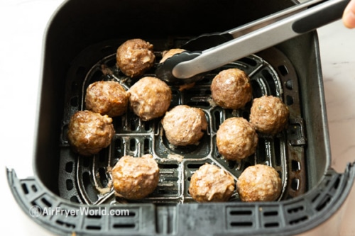 Turning partially cooked meatballs with tongs