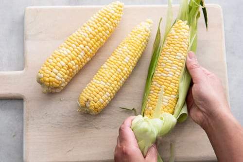 Peeling the husk off of corn on the cob