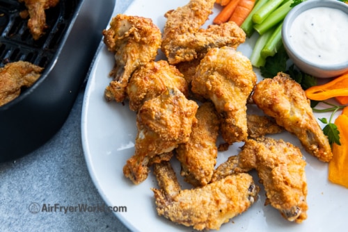 Parmesan wings on a plate with vegetables and ranch