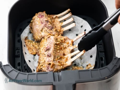 Using tongs to flip the lamb rack
