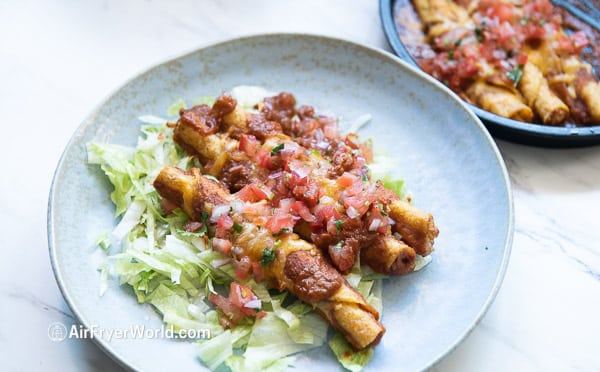 Taquitos on a plate over a bed of lettuce