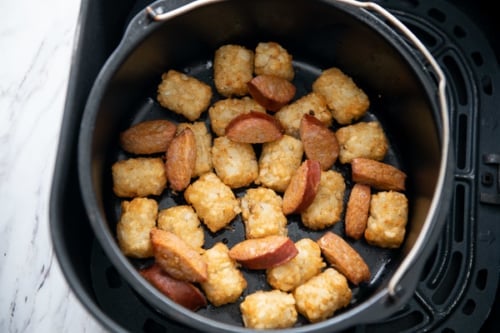 Sausage added to the cooked tater tots in the baking bucket