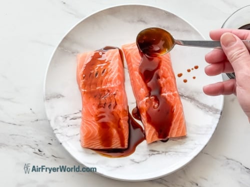 adding teriyaki sauce to salmon fillets