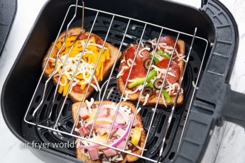 Wire rack on uncooked toast pizzas in air fryer basket