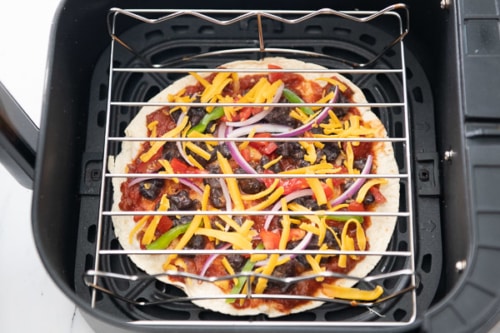 Wire rack placed over pizza to keep toppings from flying off
