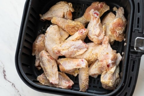Raw chicken wings in air fryer basket