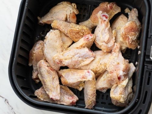 Raw chicken wings in air fryer basket