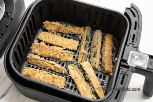 Uncooked zucchini fries in air fryer basket