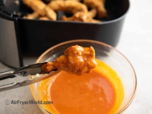 Dipping chicken wing into buffalo sauce