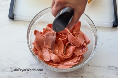 spraying hot dog with oil