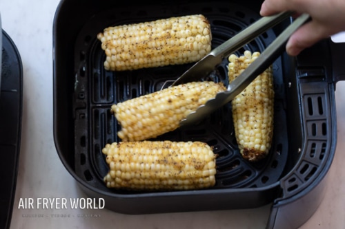 Turning corn in air fryer with tongs